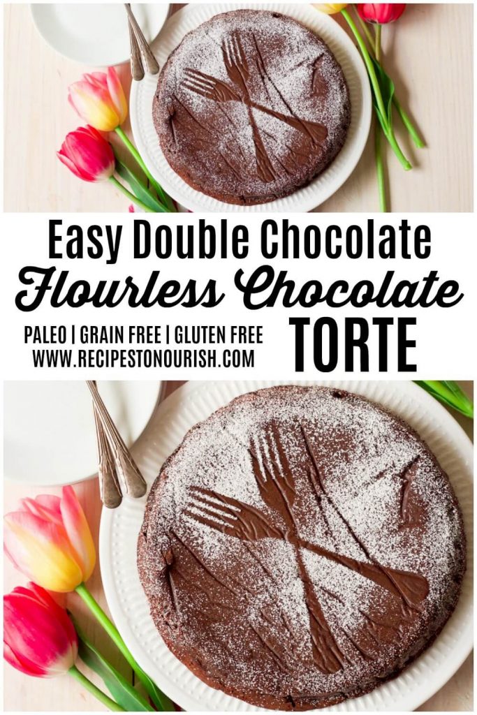 Chocolate torte cake dusted with powdered sugar making two forks pattern next to tulips.