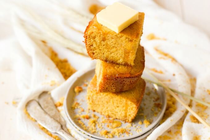 Stack of cornbread slices with butter and honey drizzle.