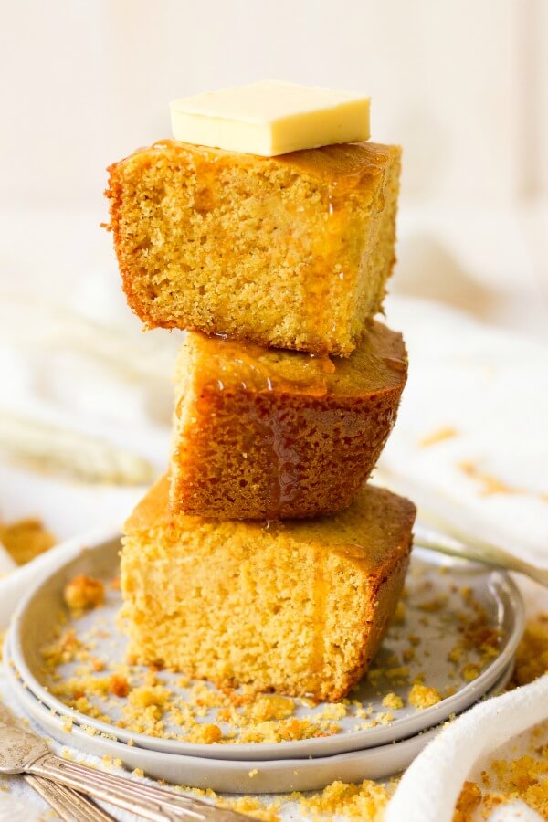 Stack of cornbread slices with butter and honey drizzle.