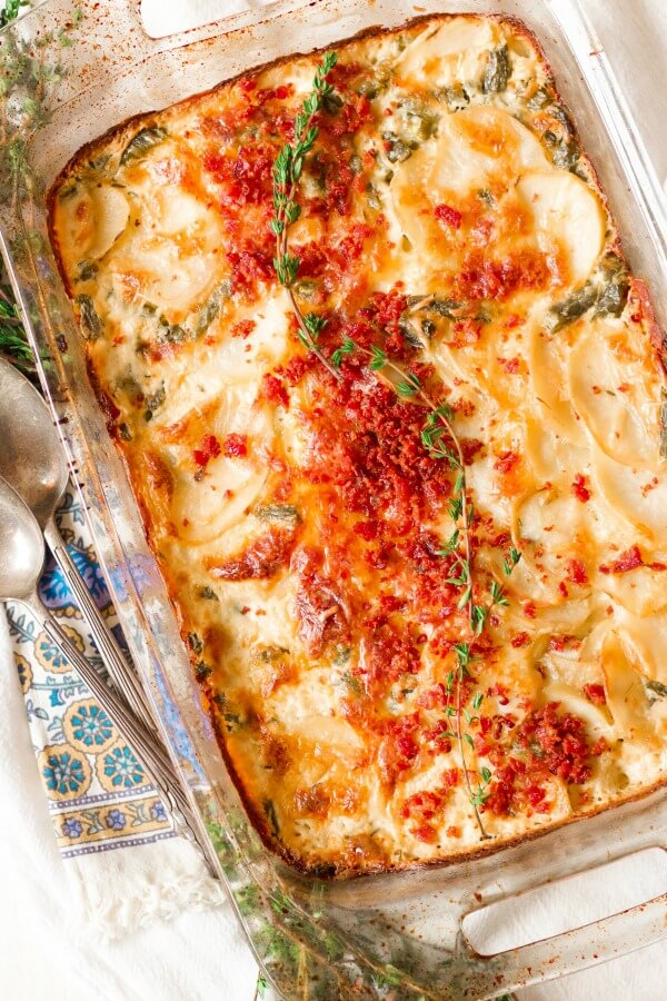 Scalloped potato casserole with bacon and thyme on top.