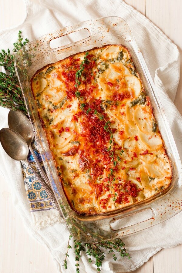 Scalloped potato casserole with bacon and thyme on top.