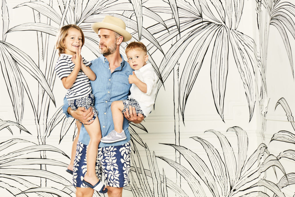 Father holds two sons who are all wearing the same swim trunks.