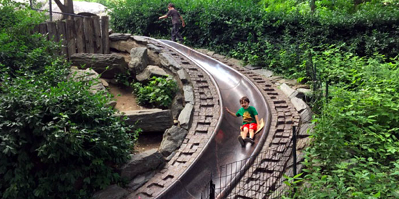 Kid slides down granite slide.