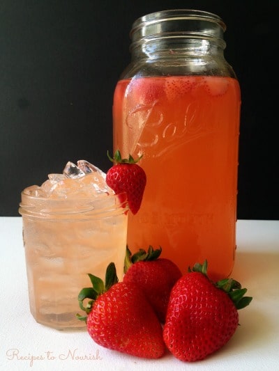 Strawberry Ginger Switchel in a mason jar and served over ice with fresh strawberries.