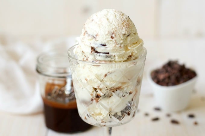 Ice cream in a glass with chocolate fudge sauce in a jar in the background.