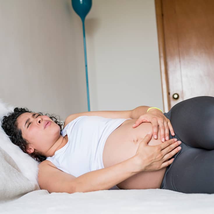 pregnant woman lying on bed suffering from pubis diastasis