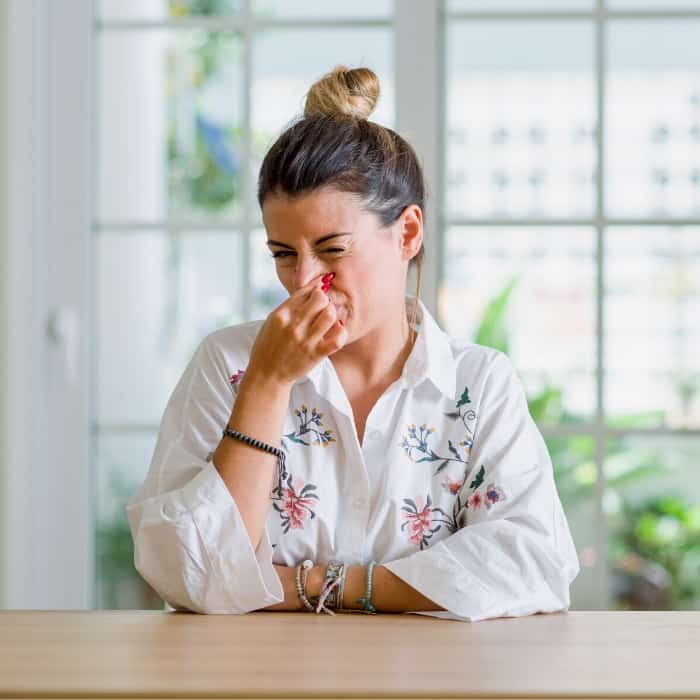 woman holding her nose from early pregnancy symptoms