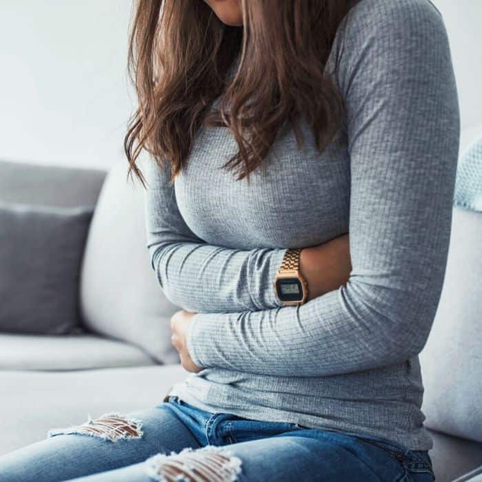 woman holding her abdomen from cramping.