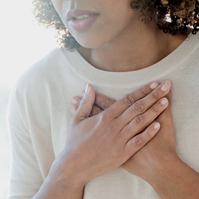 woman holding her chest with a shortness of breath