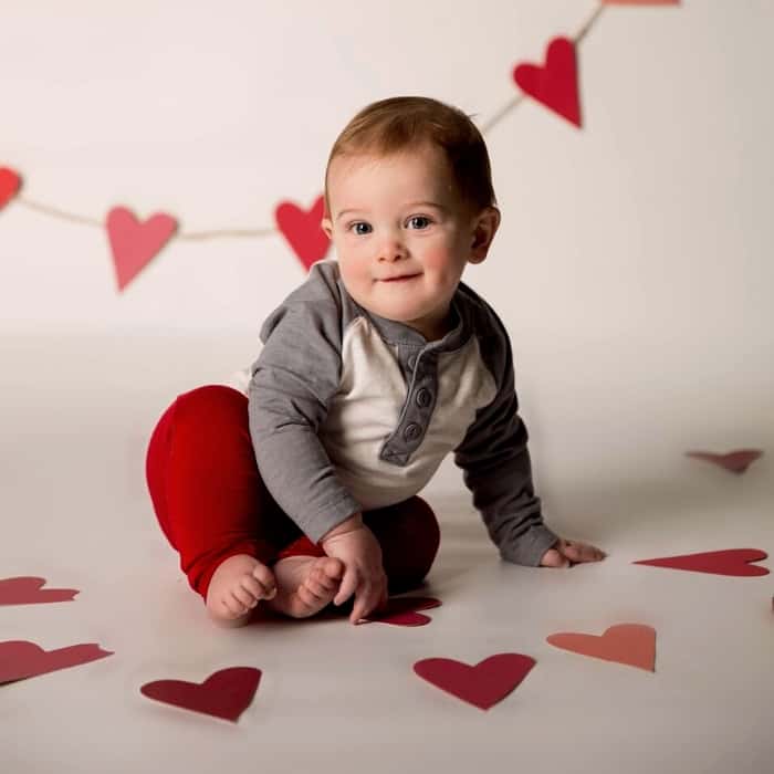 Little boy sitting among cut out hearts for a valentine's day shoot