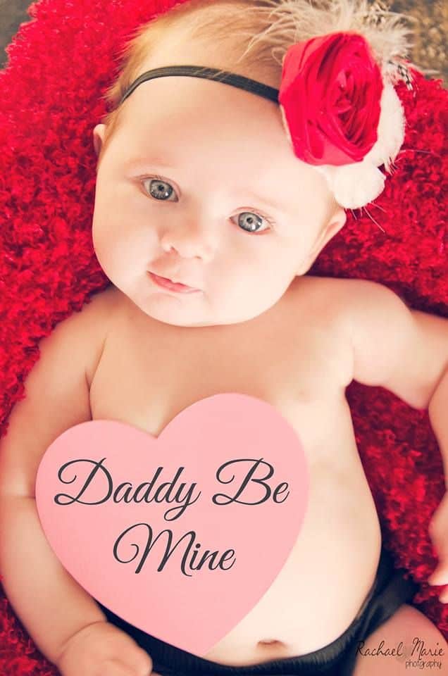 Baby with red flower headband and Daddy Be Mine heart note on their tummy - Baby's First Valentine's Day Photo shoot