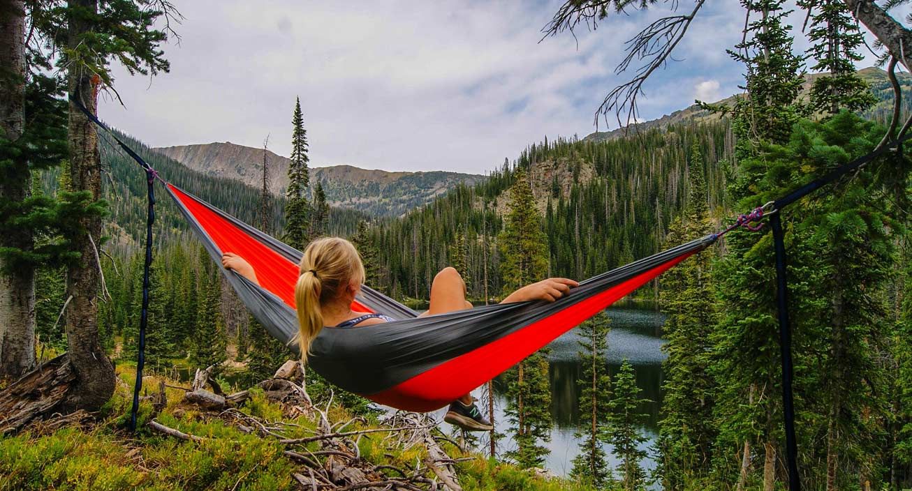 A girl outside on a hammock enjoying the outdoors. 