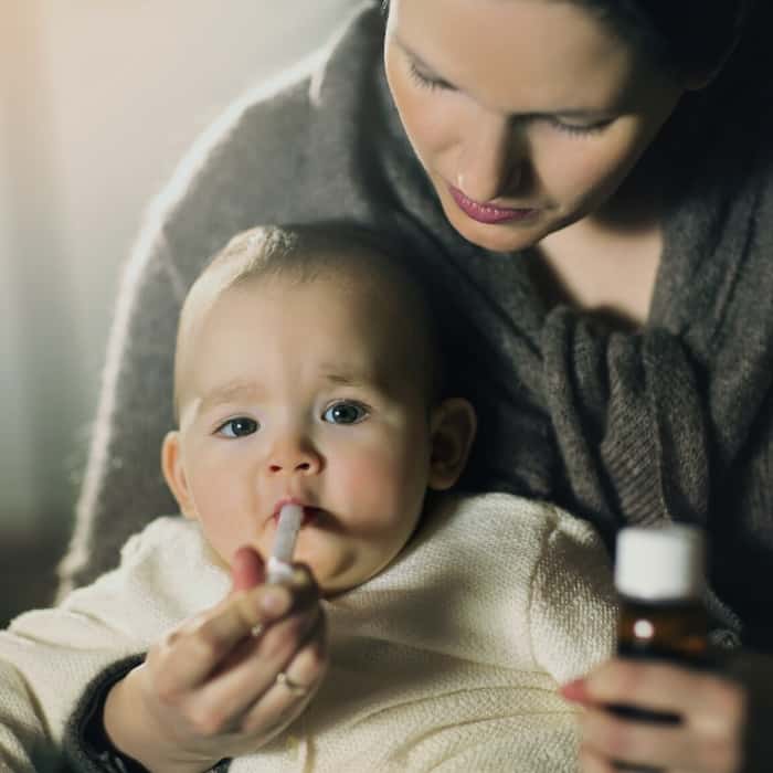 mom giving baby medicine with a dropper