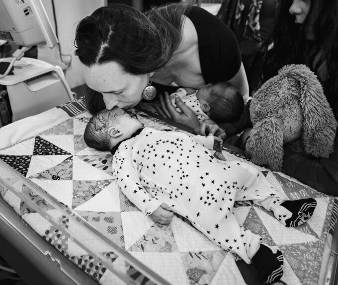 A grieving mother of twins holding one of her baby's and kissing the baby that she lost in the NICU.