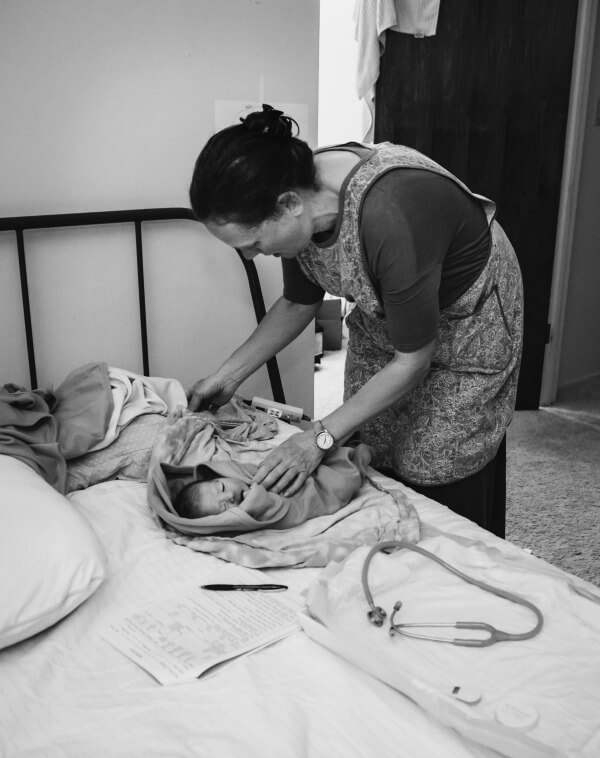 Newborn baby getting his newborn exam at home by his midwife after his home birth.