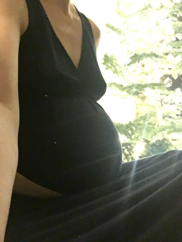 Photo of a pregnant mother with twins sitting by a Christmas tree.