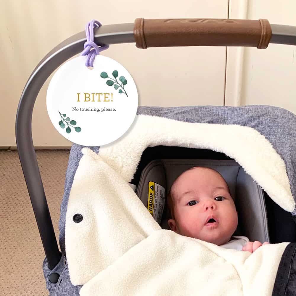 baby in car seat with an I Bite car seat do not touch tag