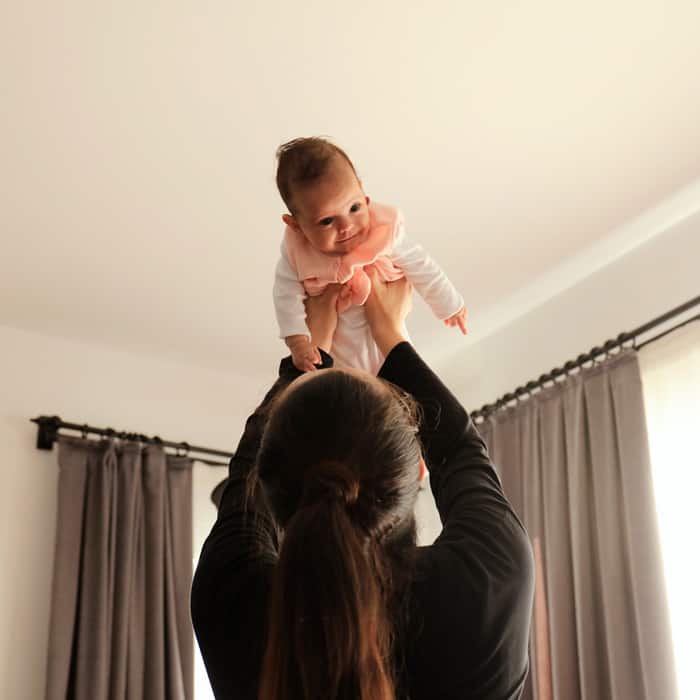 mom with a healthy body image holding newborn baby up over her head