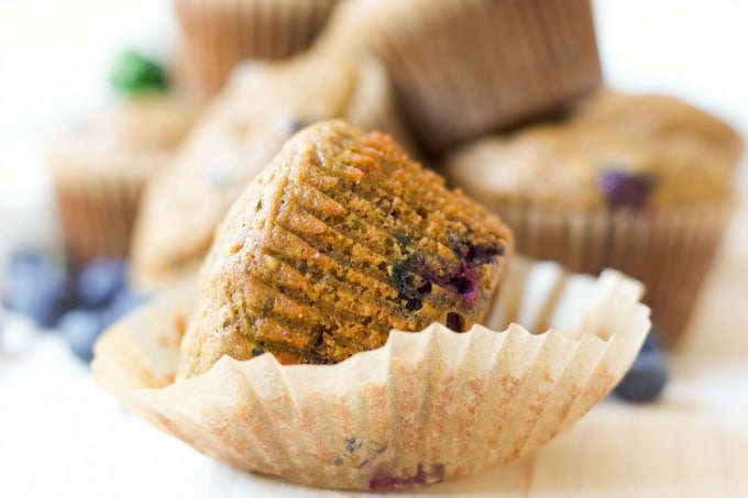 Muffins in wrappers with fresh blueberries. 