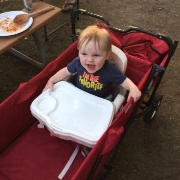 toddler sitting in portable chair in a foldable wagon