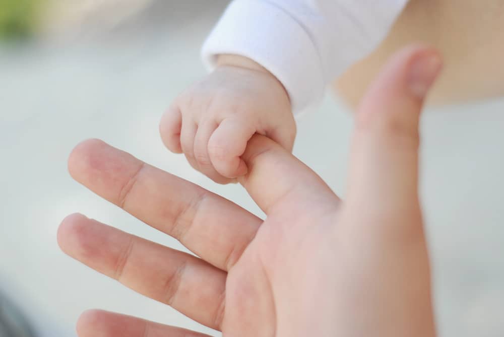 newborn holding adult finger baby on a budget