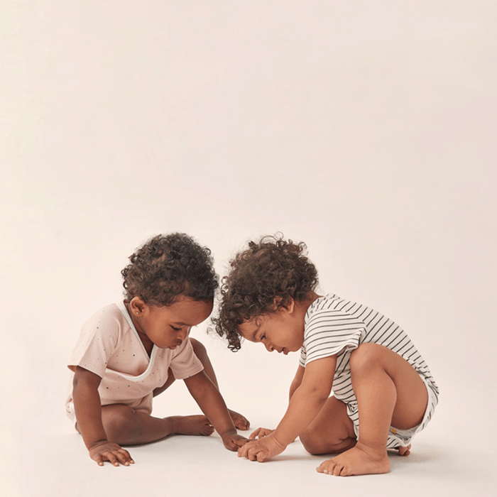 two toddlers playing while wearing organic onesies