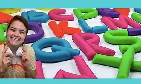 Woman smiling in front of play dough letter background