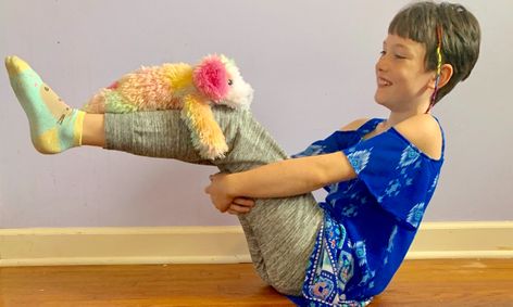 Young kid doing yoga with stuffed animal